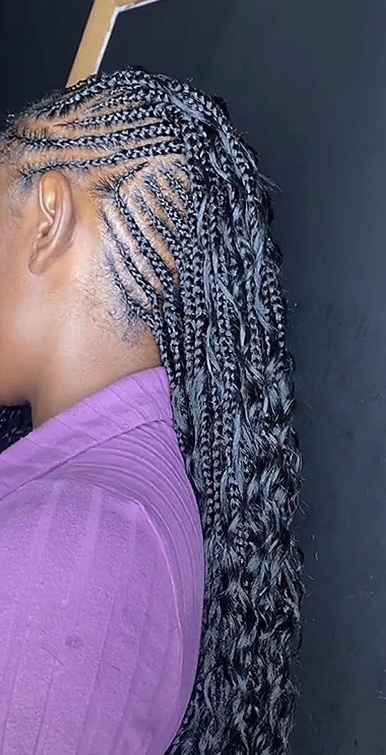 Boho knotless braids with curly strands left out, side view.